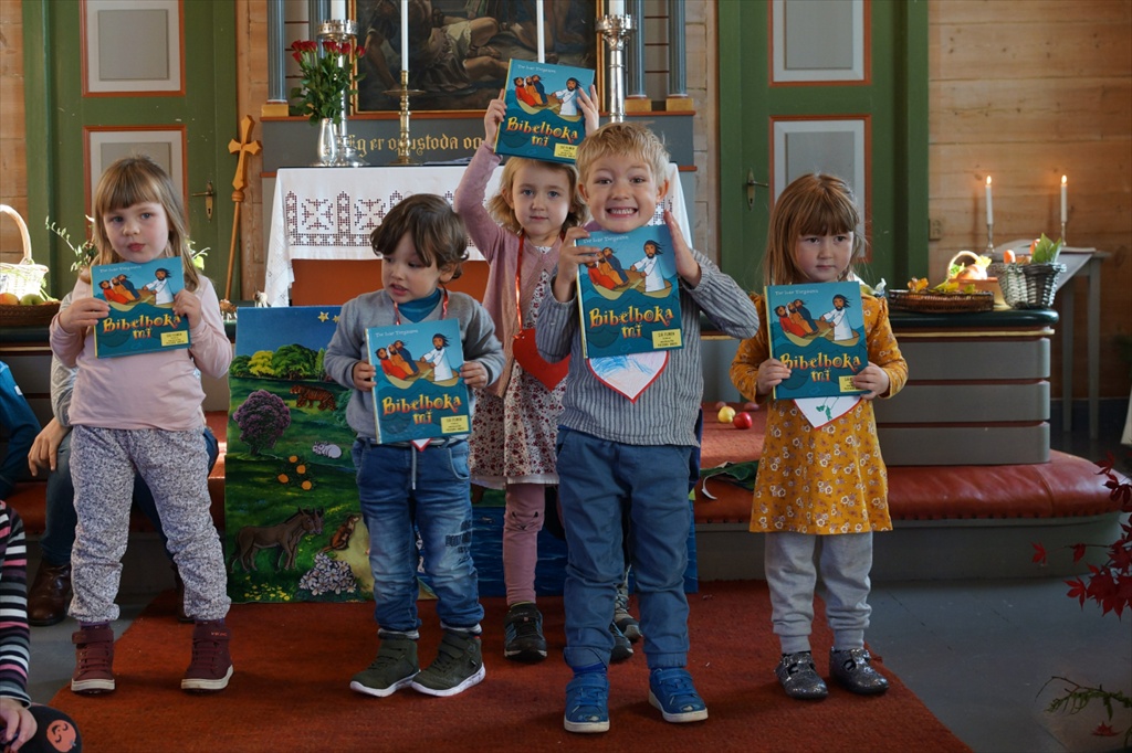 Foto av fireåringar med bøker foran alteret i Tjugum kyrkje